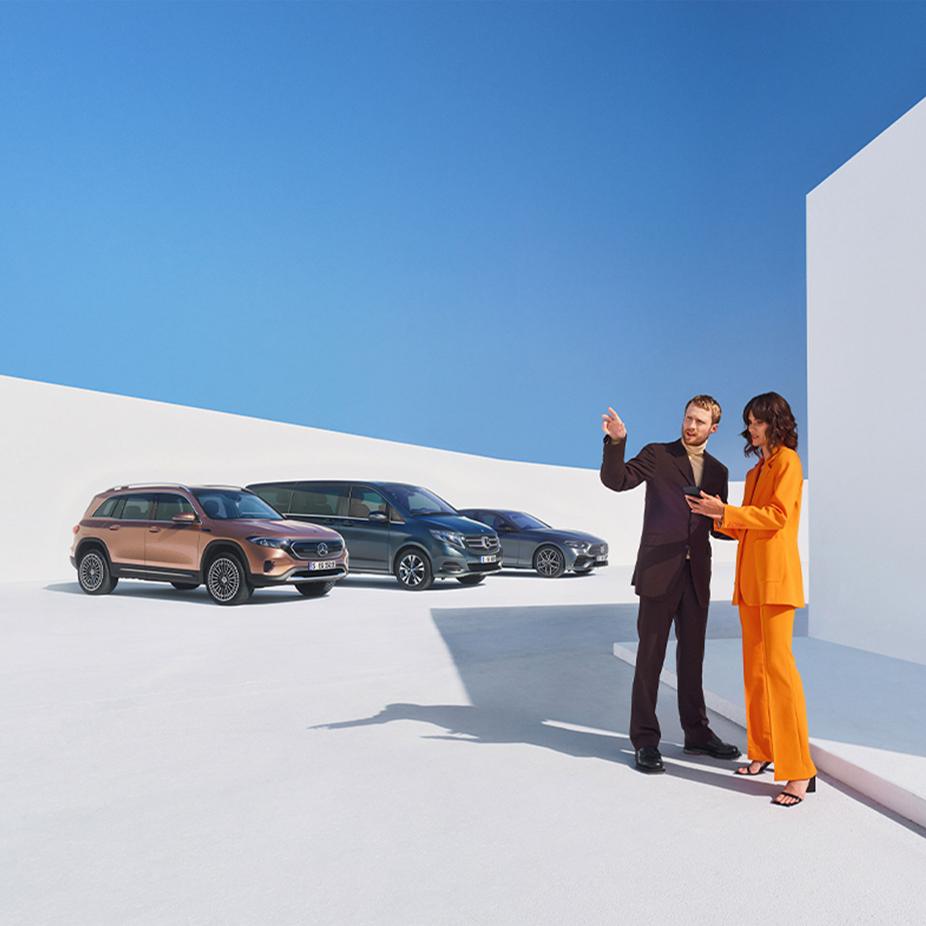 Extraopțiuni digitale pentru clienți persoane juridice | Extraopțiuni digitale | Mercedes-Benz Un bărbat și o femeie în fața mai multor autovehicule Mercedes-Benz.