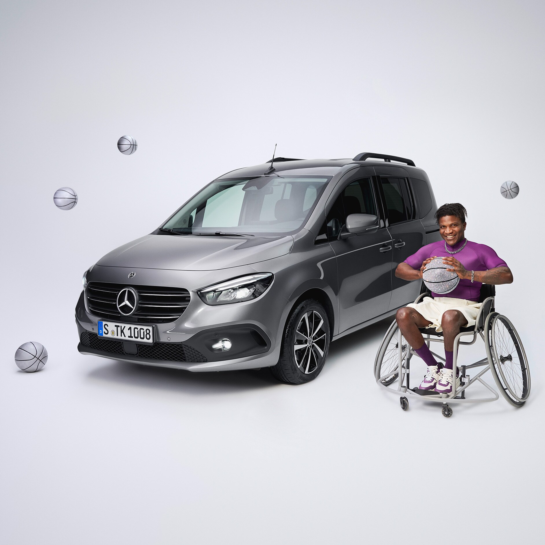 Consultanță | Sisteme de asistență la rulare | Mercedes-Benz Modelul Mercedes-Benz Clasa T transformat pentru persoanele cu dizabilități, într-o vedere frontală oblică și un jucător de baschet în scaun cu rotile în prim-plan stânga.