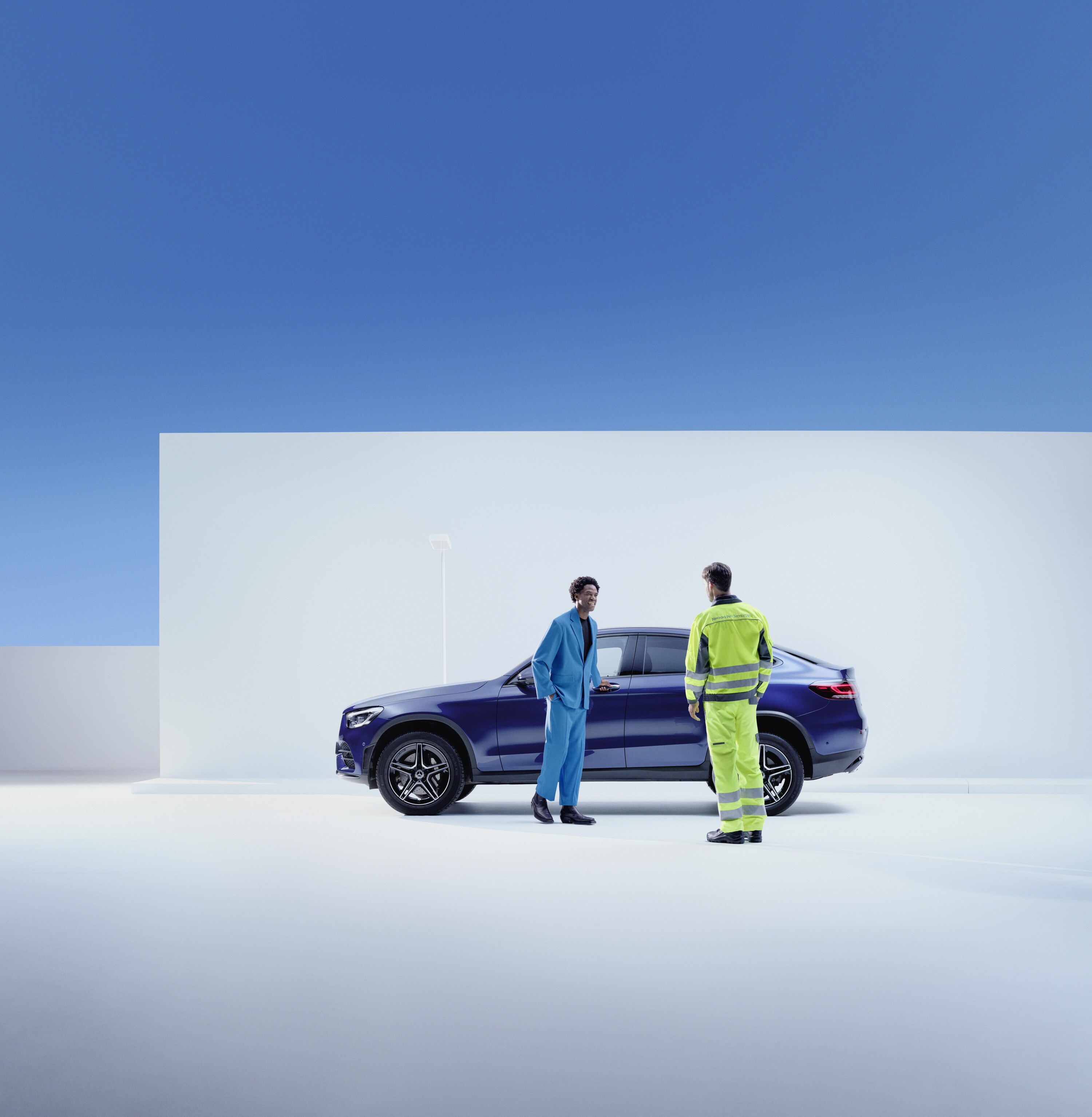 Asistență în caz de defecțiune | Mercedes-Benz O persoană din service-ul Mercedes-Benz stă lângă un client, într-o parte a autovehiculului său Mercedes-Benz.